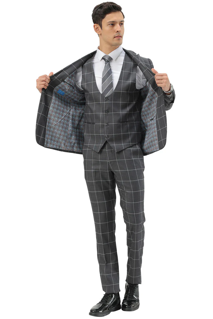 Men's slim fit grey windowpane plaid suit. Includes a two-button blazer with peak lapels, matching vest, and tapered trousers. Contrasting white plaid pattern, patterned lining.
