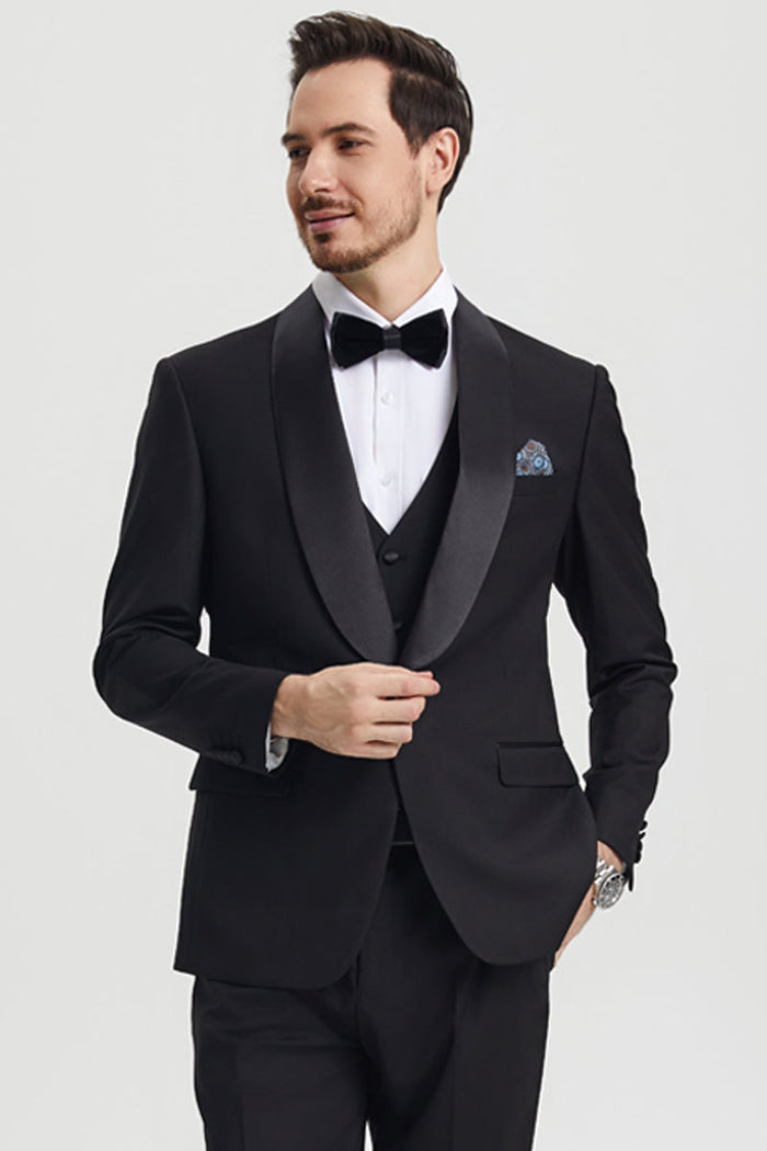 Stacy Adams black one-button tuxedo with shawl lapel. Fitted, tailored design with sharp shoulders. Features a vest, satin lapel, and patterned pocket square for a streamlined formal look.
