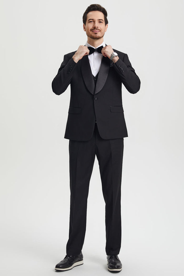Stacy Adams men's black one-button tuxedo with shawl lapel. Fitted jacket, flat-front trousers, and a structured silhouette. Features smooth, solid black fabric and satin details.
