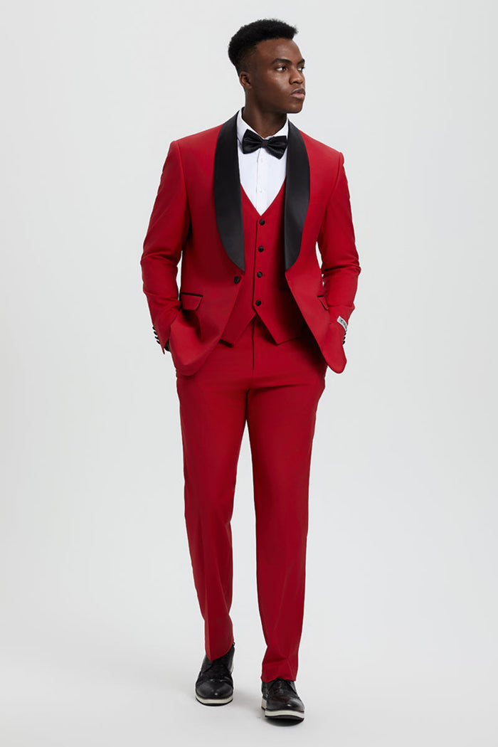 Red Stacy Adams tuxedo with shawl lapel. Single-button jacket, matching vest, and tailored trousers. Black lapel accents, paired with a white dress shirt for a formal look. Smooth, structured material.

