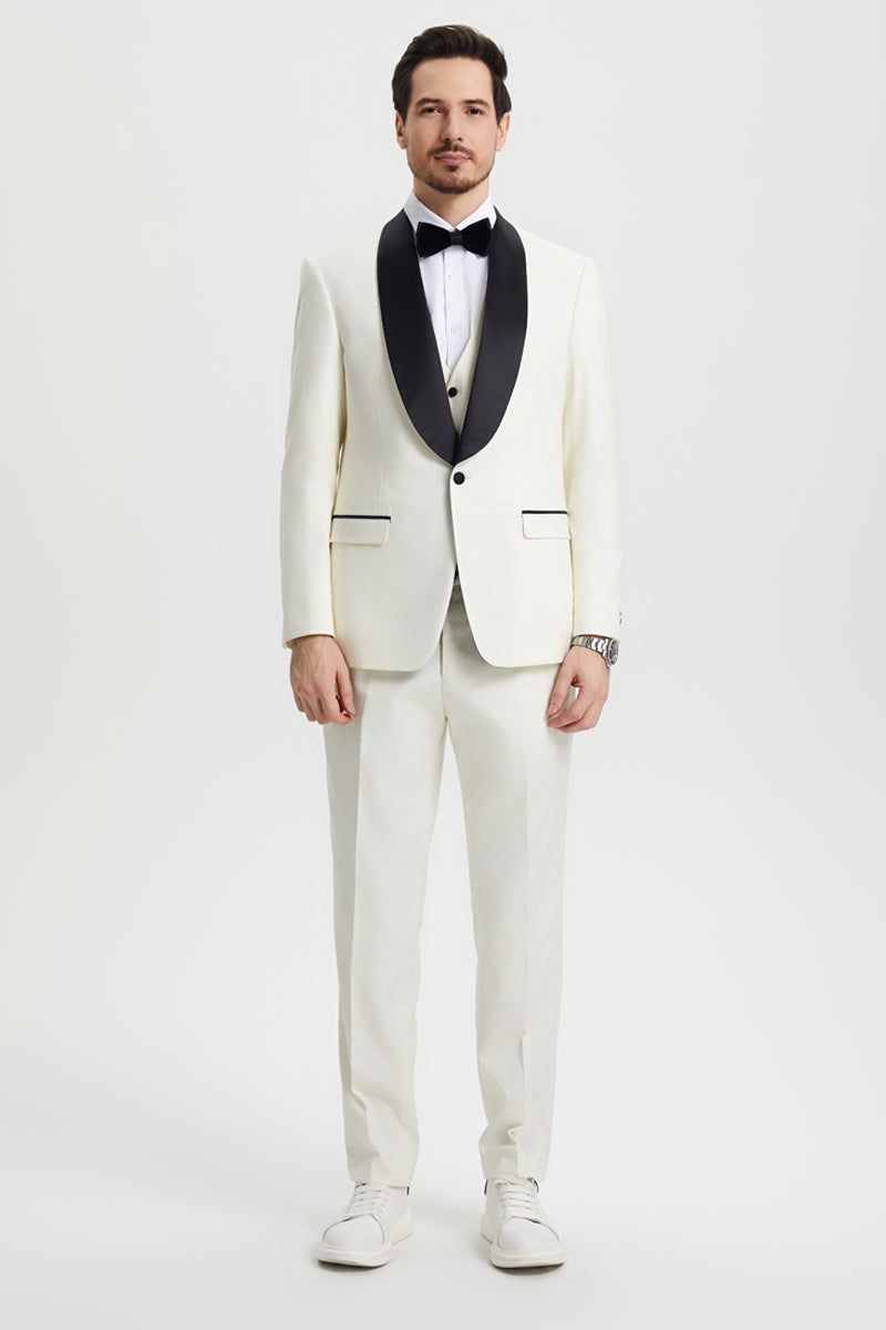 Ivory Stacy Adams one-button tuxedo with black shawl lapel. Includes jacket, vest, and straight-leg trousers. Smooth fabric, classic design.
