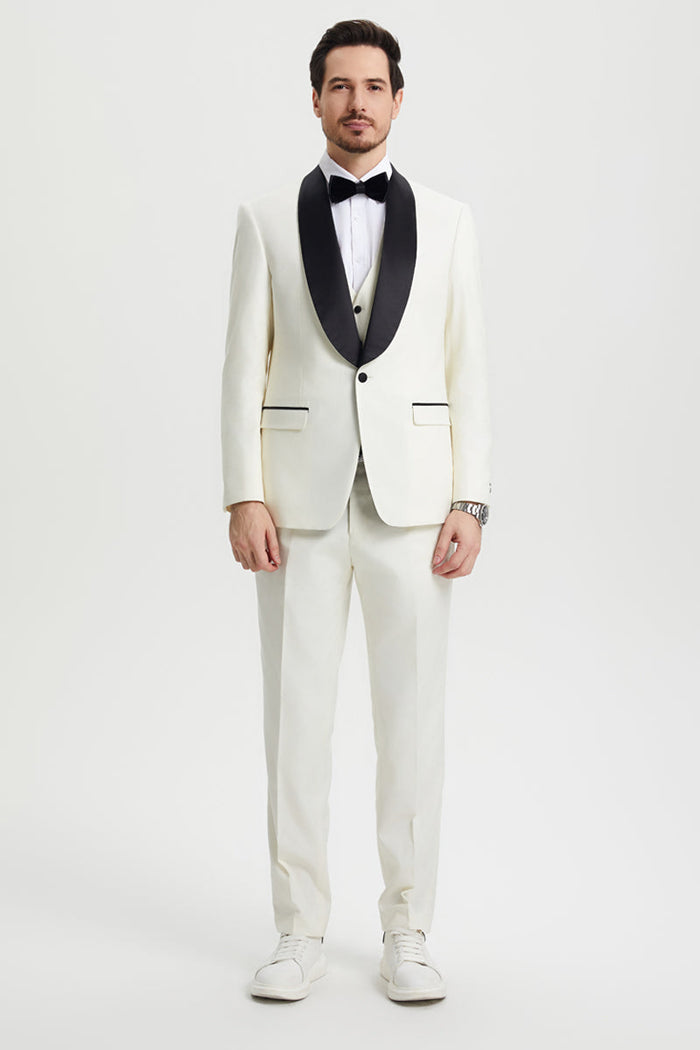 Ivory Stacy Adams one-button tuxedo with black shawl lapel. Includes jacket, vest, and straight-leg trousers. Smooth fabric, classic design.
