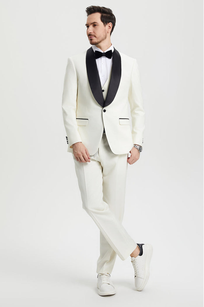 Ivory Stacy Adams one-button tuxedo with shawl lapel. Fitted shape, matching vest, and contrasting black lapel/pocket accents. Tailored trousers complete the look.
