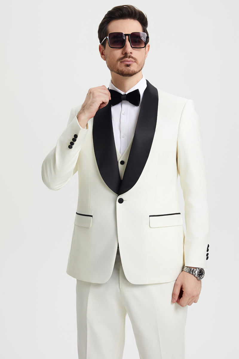 Ivory Stacy Adams one-button tuxedo with black shawl lapel and vest. Black piping accents pockets, structured fit, smooth fabric. Ivory pants, 3-button cuffs. Formal.