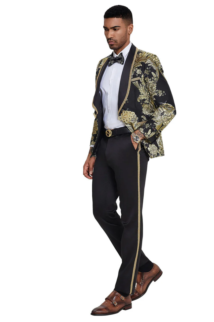 Men's black tuxedo with shiny paisley jacket (black & gold). Shawl lapel, tailored trousers (gold stripe), white shirt, and black bow tie complete the look.
