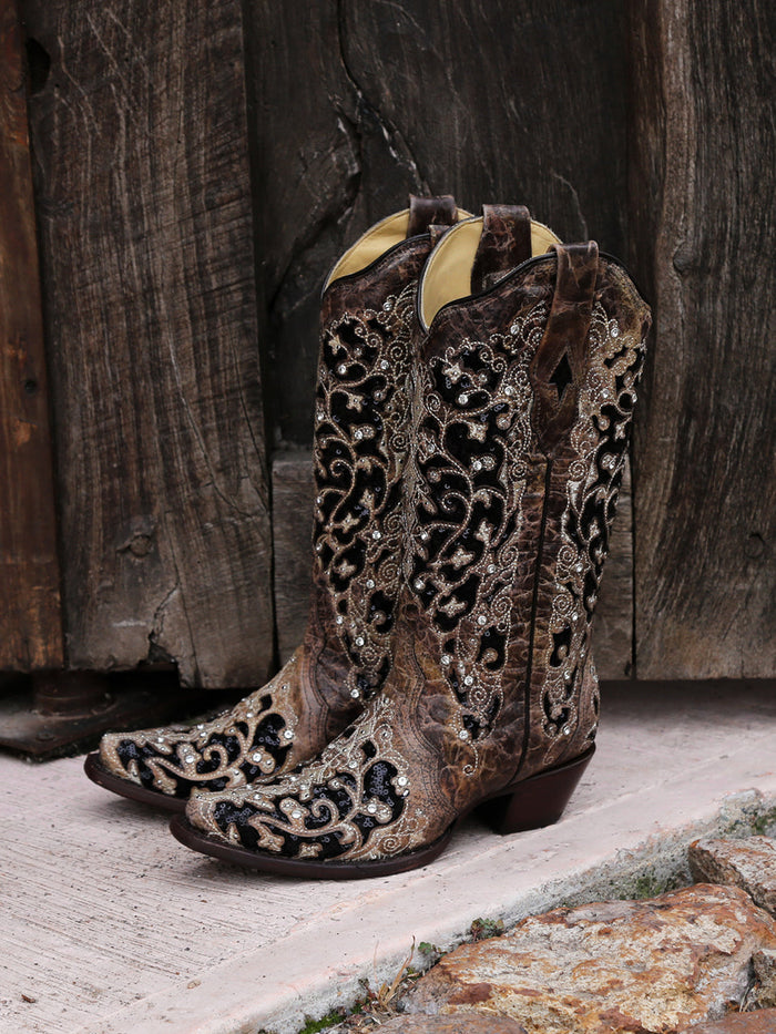 Corral women's black glitter inlay cowboy boots: brown exterior, black floral patterns, silver embellishments. Snip toe design with a structured, lower heel silhouette.
