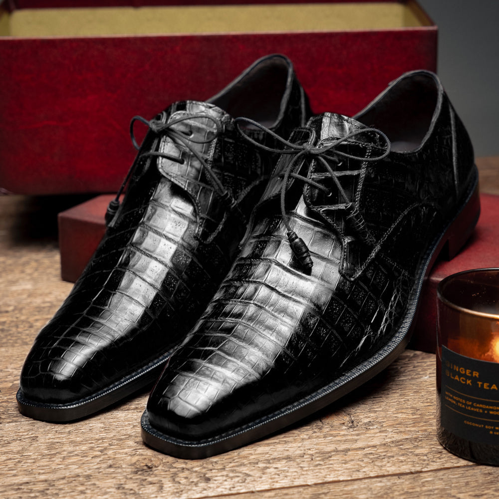 Black Mezlan Anderson derby shoes with a crocodile skin texture. Polished finish, pointed toe, and lace-up closure. Flat, contrasting durable sole.
