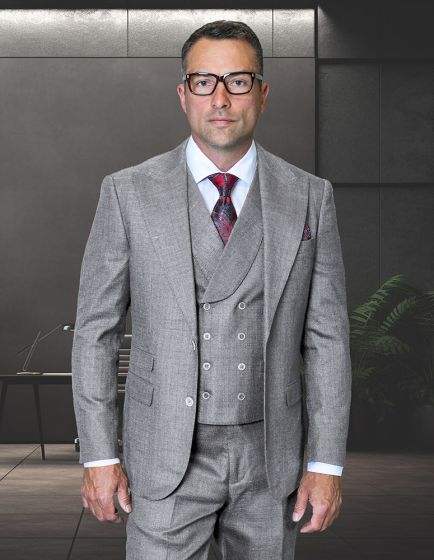 The Statement mens 3 piece suit features a modern fit with a peak lapel. It is made from 100% wool and presented in a light gray color. The suit consists of a tailored jacket, waistcoat with buttons, and matching trousers. The jacket has two front pockets and detailed stitching along the edges.