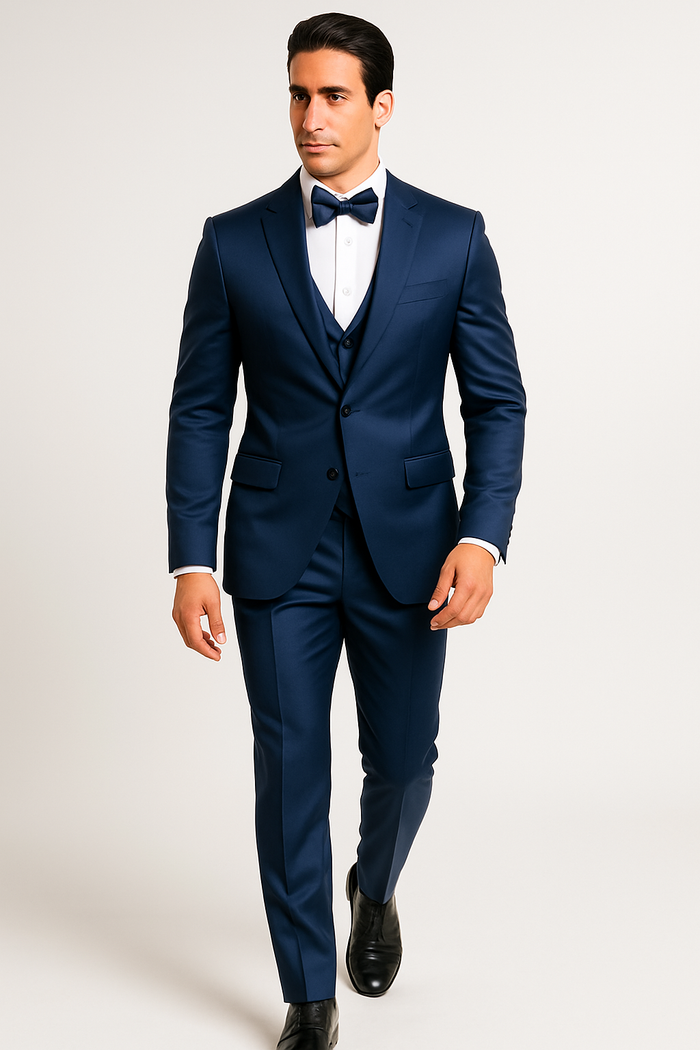 Blue tuxedo set: tailored jacket, waistcoat, pants, and bow tie. Deep blue, smooth, slightly shiny fabric. Jacket: notch lapel, single-button. Waistcoat: V-neck. Pants: slim-fit, flat front. Well-fitted, coordinated.
