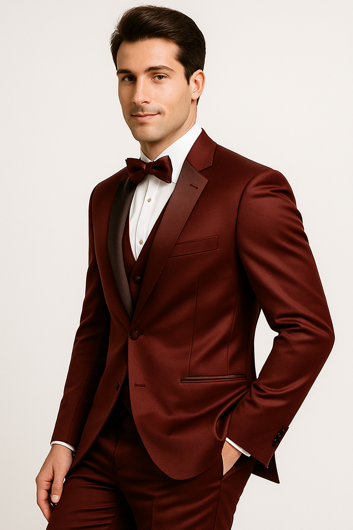 Burgundy Majesty tuxedo set: fitted jacket (satin shawl collar), white shirt, bow tie. Tailored burgundy pants with sheen. Includes a three-piece vest, color-coordinated. Smooth fabric.
