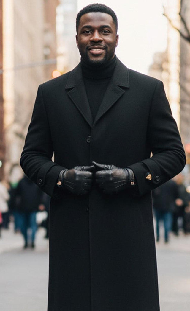 Men's black, single-breasted, full-length topcoat. Tailored straight cut with collar. Dark matte fabric. Button closure and slightly flared sleeves with cuff buttons.
