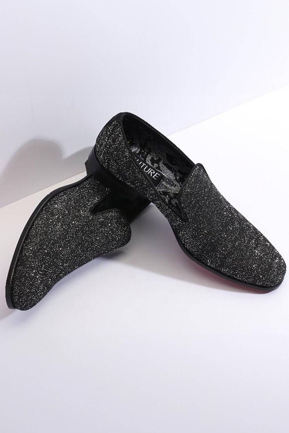 Black tuxedo shoes from 1910. Sleek silhouette with pointed toe, textured black glitter finish. Low profile, flat heel, no laces. Smooth leather trim. Patterned interior visible.