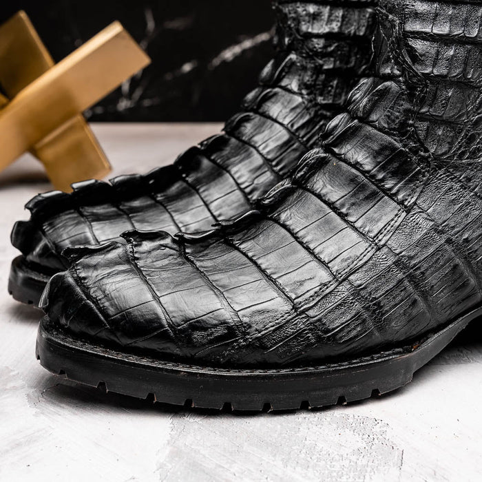 Marco Di Milano Marlboro cowboy boots in black hornback crocodile. Rounded toe, tractor sole, and tall, slouchy shape. Features pronounced scales and textured leather.
