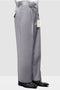 Light grey Italian wool wide-leg men's dress pants. Loose fit, straight cut, soft texture. Features: waistband, belt loops, single button, front pleats, side pockets. Clean silhouette, worn above black dress shoes.

