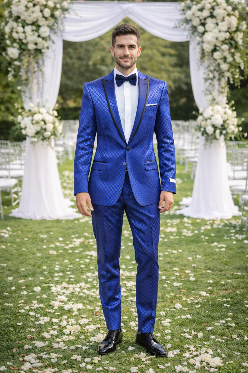 Navy checkered slim fit tuxedo by Giovanni Testi. Dark blue patterned fabric with diamond check. Single-breasted jacket, notched lapel with black trim. Matching slim fit trousers. White shirt, black bow tie. Tailored, slim fit silhouette.

