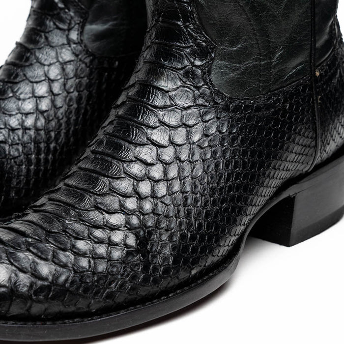 Black python cowboy boots by Marco Di Milano. Round toe, textured black python skin with a scaled pattern. Fitted silhouette, slightly raised heel, smooth upper with contrasting finish.
