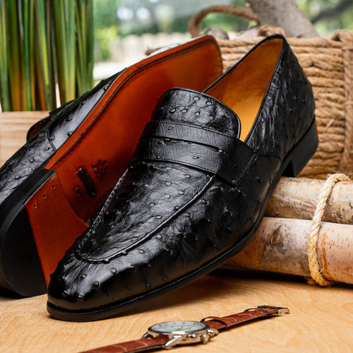 Black Mezlan Lisbon penny loafers in ostrich quill leather. Features classic penny band, textured surface, and tan interior lining. Flat sole with slight heel.

