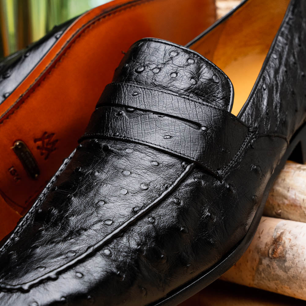 Black Mezlan Lisbon penny loafers in ostrich quill leather. Textured surface with small bumps, classic penny strap, and rounded toe. Tan interior. Traditional loafer outsole.
