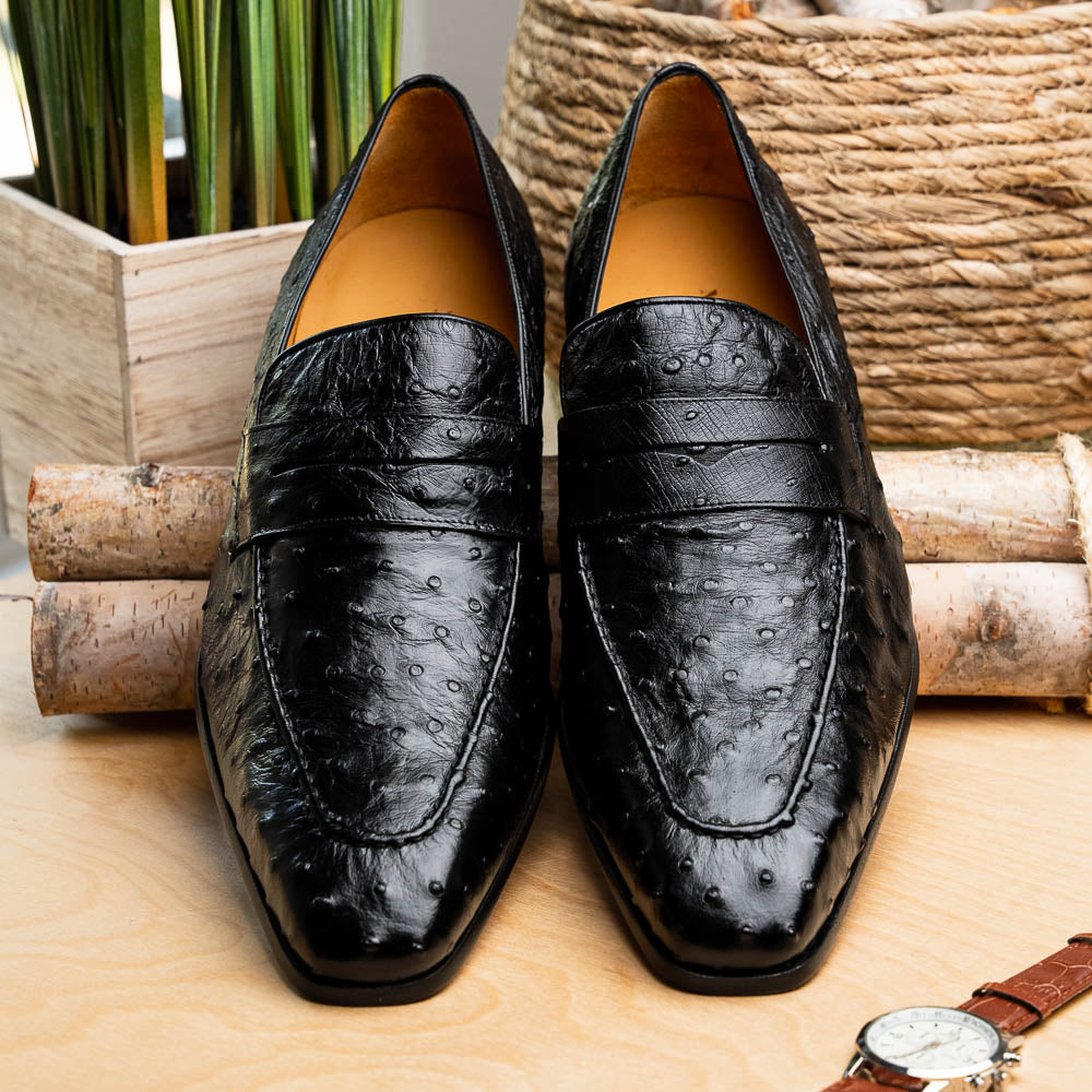 Black Mezlan Lisbon penny loafers. Ostrich quill leather upper with pointed toe and horizontal band. Tan lining. Flat sole.
