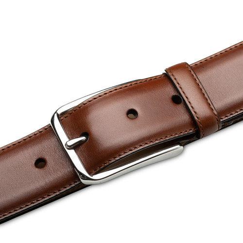 Mezlan cognac calfskin belt with a smooth, elongated strap and polished silver buckle. Features neat stitching, adjustable perforations, and a primary cognac color.

