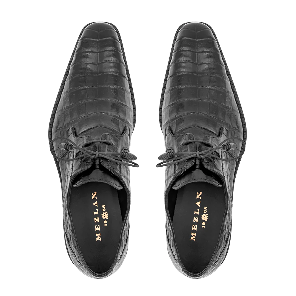 Black Mezlan Anderson derby shoes with crocodile texture. Pointed toe, leather, lace-up. Black insole with gold branding. Flat black outsole. Slender profile.
