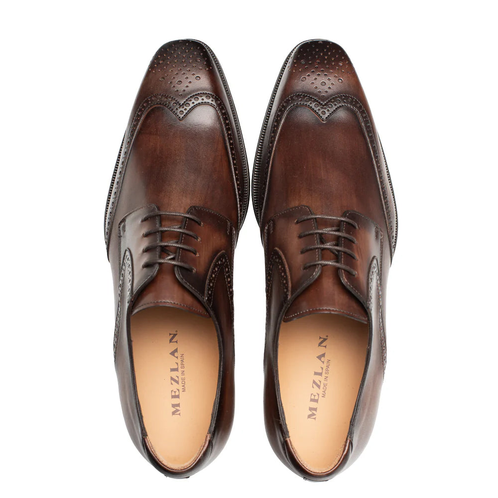 Mezlan Tasso Wingtip Derby in chestnut. Polished leather, rounded toe, brogue detailing. Classic lace-up closure, sturdy sole. Rich chestnut color, sleek silhouette.
