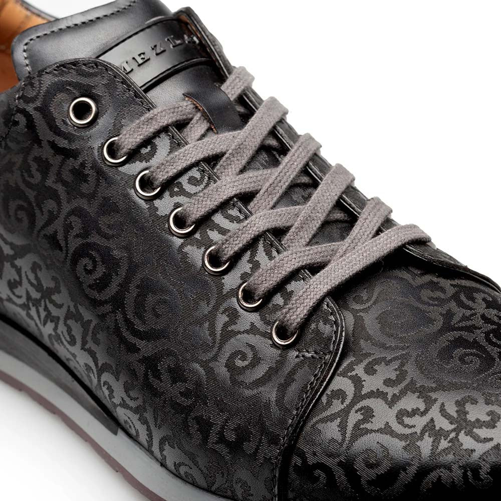 Black Mezlan Portico sneaker with laser-printed pattern. Features a textured upper, round toe, and grey laces. Contrasting rubber sole with embossed logo on the tongue. Predominantly black with subtle shade variations.
