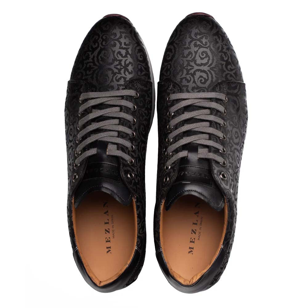 Mezlan Portico black sneaker: low profile, semi-shiny upper with swirling pattern. Round toe, grey laces, light brown interior lining. Rubber sole for slight elevation.
