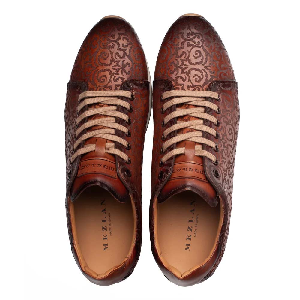 Cognac rust Mezlan Portico sneaker. Rounded toe, low-top. Laser-printed pattern on soft leather upper. Tan lace closure, padded collar. Neutral fabric lining with brand logo.
