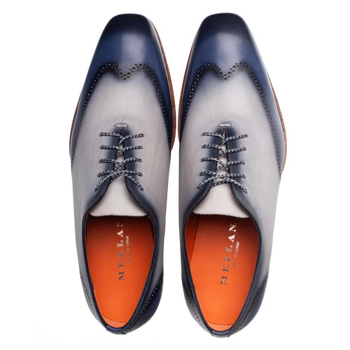 Mezlan Almagro Oxford: Two-tone navy/pearl grey leather with a pointed toe. Features six eyelets, decorative perforations, and an orange leather lining. Light brown sole provides contrast.
