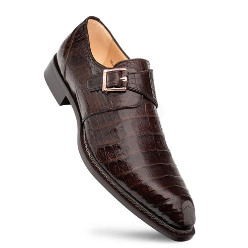 Mezlan Gigolo monk strap shoe in rich brown crocodile leather. Pointed toe, textured pattern, and metallic buckle detail. Sturdy sole with slight heel and light-colored lining for a refined look.
