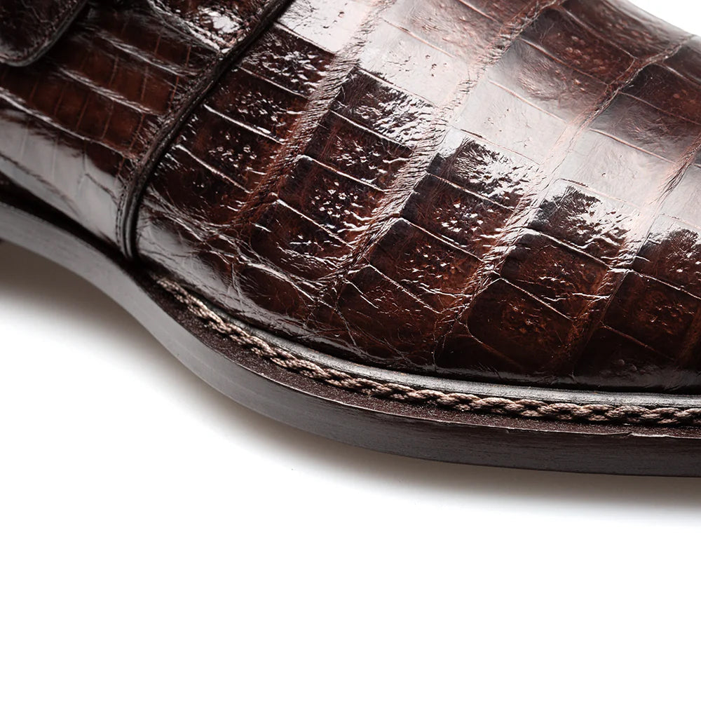 Brown Mezlan Gigolo monk strap. Sleek, elongated silhouette with textured brown crocodile leather upper. Single monk strap with metal buckle closure. Dark brown leather sole with stitch detailing. Rounded toe.
