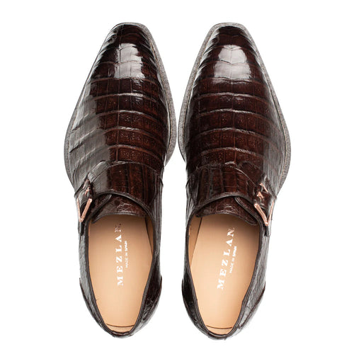 Mezlan Gigolo monk strap shoe: glossy, dark brown crocodile leather upper with textured pattern. Pointed toe, single strap with metal buckle. Tan interior lining.
