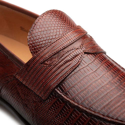Mezlan Mayor cognac penny loafer. Features a rounded toe, smooth, reptilian-textured leather upper. Rich cognac brown with varied shades. Penny keeper strap detail. Durable, flat outsole.
