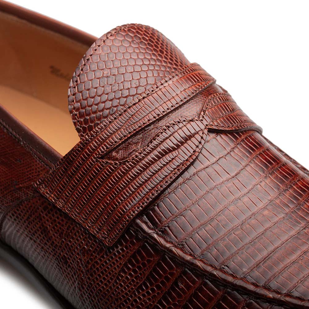Mezlan Mayor cognac penny loafer. Features a rounded toe, smooth, reptilian-textured leather upper. Rich cognac brown with varied shades. Penny keeper strap detail. Durable, flat outsole.
