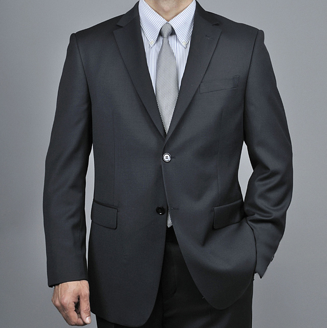 Dark gray, slim-fit suit. Two-button, notched lapel design. Single breast pocket, two flap pockets. Smooth, tailored fabric with minimal texture.
