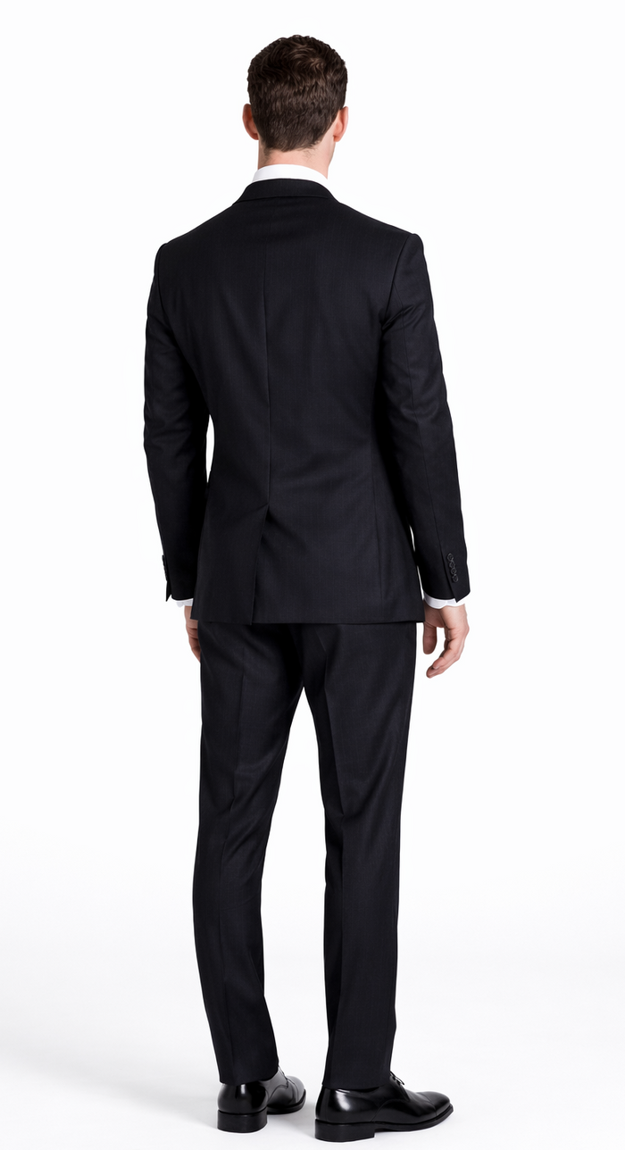 Black wool suit back view: two-button closure, striped pattern (black, gray, navy). Standard-cut jacket with back vent. Straight-leg trousers. Black shoes.
