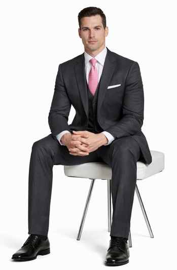 Mantoni charcoal wool suit: fitted, two-button, notched lapel. Includes white shirt, pink tie, and straight-cut trousers. Features side pockets and shiny black shoes. Tailored, sleek silhouette.
