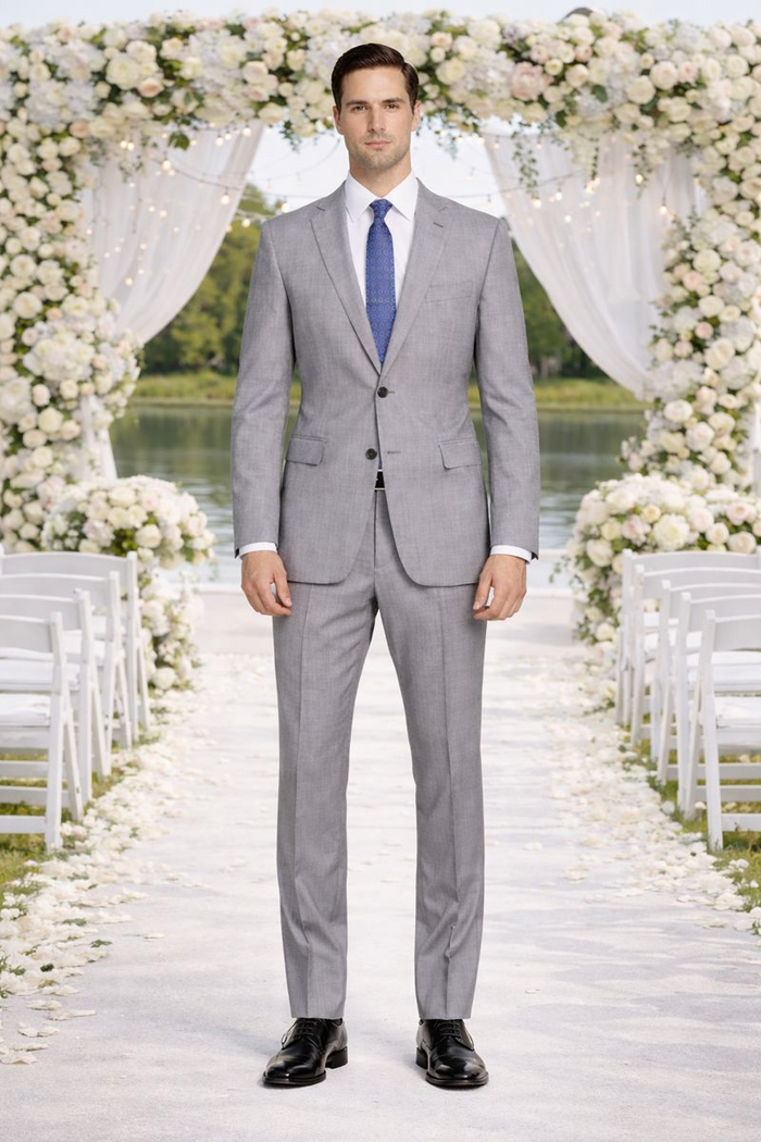Mantoni light gray wool suit: modern/slim fit, notched lapel, two pockets. Paired with white shirt, blue patterned tie, straight-cut trousers. Sleek, contemporary style.
