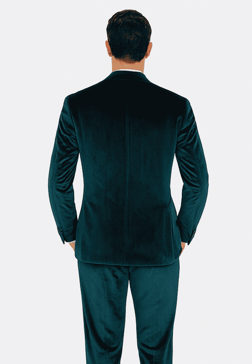 Teal velvet men's suit: two-piece, peak lapel, slim fit. Soft, textured velvet in rich teal. Back view reveals tailored shape, single vent. Sleeves taper, showcasing a refined, slim silhouette.
