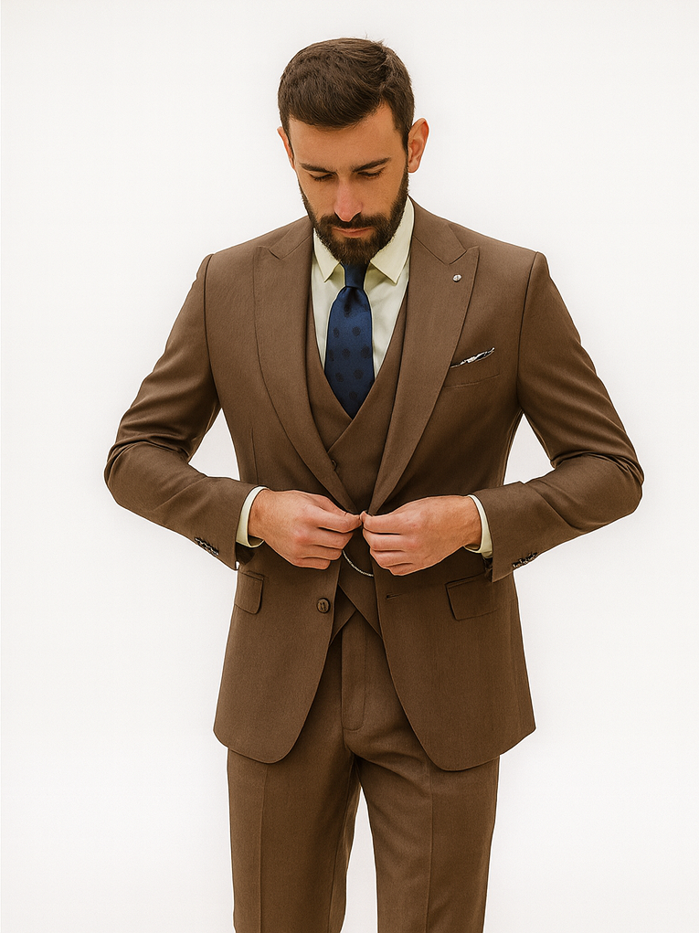 Designer brown suit with vest. Tailored fit, structured shoulders, smooth fabric. Two-button closure. Includes vest, light green shirt, navy polka dot tie, and pocket square.
