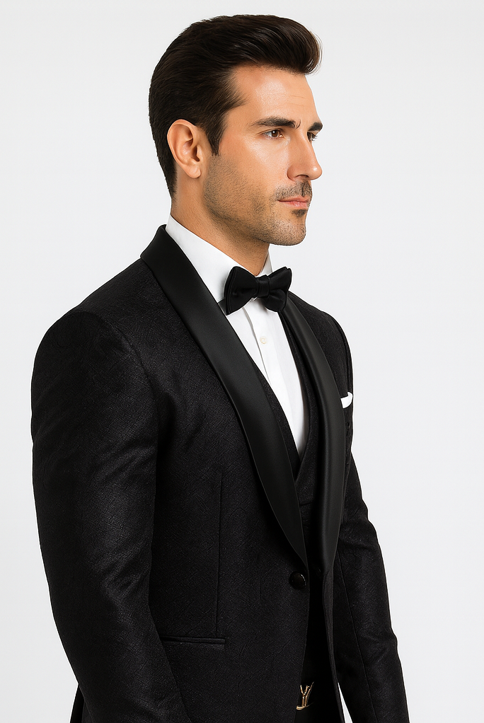 Black tuxedo with floral lace texture, satin shawl lapel, and black vest over a white dress shirt. A stylish, elegant ensemble.
