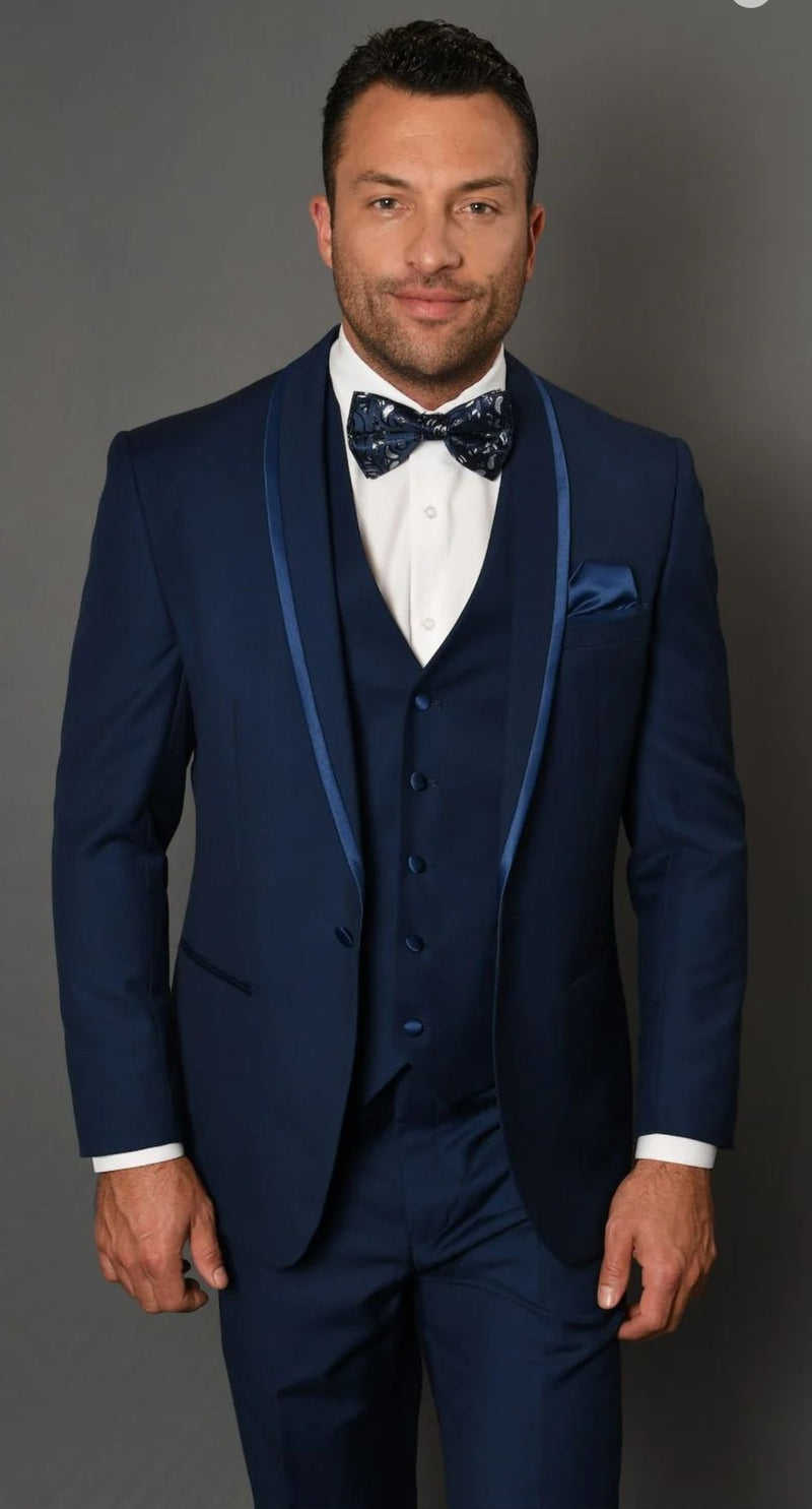 Navy blue three-piece tuxedo with blue trim, satin shawl lapel. Includes bow tie and fitted waistcoat. Smooth fabric. Elegant ensemble.
