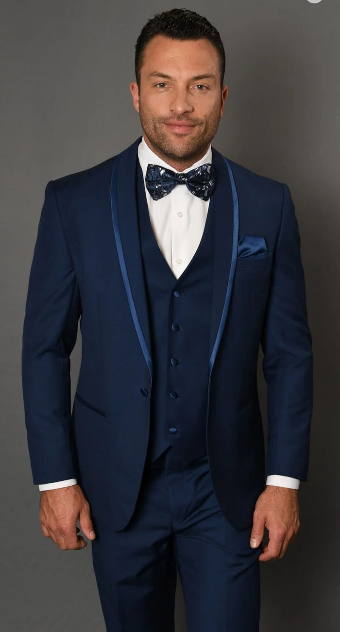 Navy blue three-piece tuxedo with blue trim, satin shawl lapel. Includes bow tie and fitted waistcoat. Smooth fabric. Elegant ensemble.
