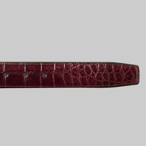 Burgundy Mezlan AO7907 alligator belt. Slim, tapered design with a smooth end. Shiny, textured alligator leather with scale pattern. Features evenly spaced adjustment holes.