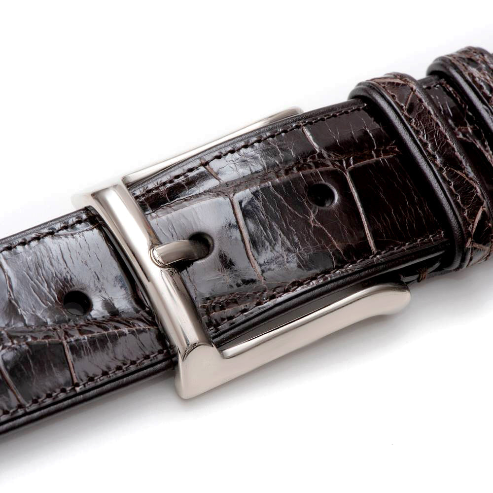 Dark brown Mezlan AO7907 alligator belt with a glossy finish. Features a distinct alligator pattern, metal rectangular buckle, and stitched edges. Offers adjustable sizing.