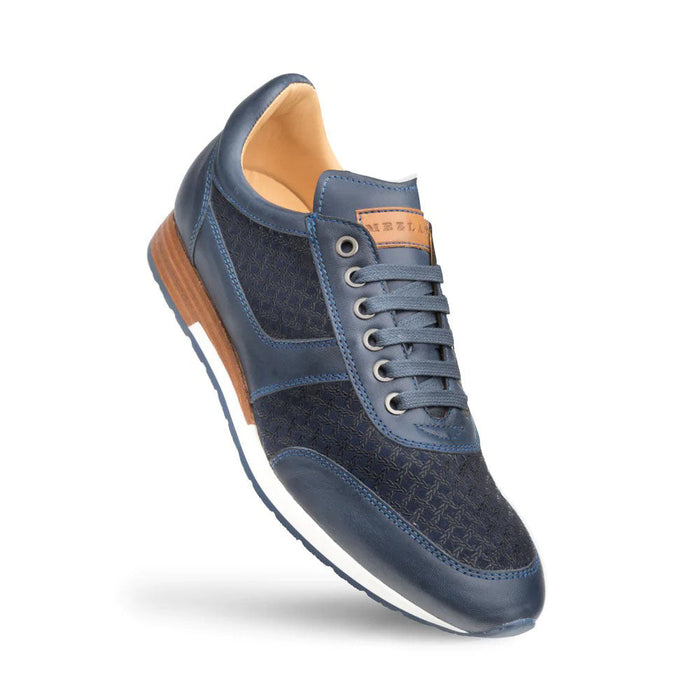Mezlan Maxim sneakers in blue calfskin. Rounded toe, patterned panel, and smooth leather accents. Lace-up closure with six eyelets and tan tongue patch. Layered wooden-effect heel on the low-profile rubber sole.
