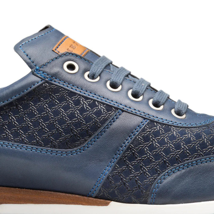 Mezlan Maxim blue calfskin sneakers. Structured design with smooth leather upper and textured detailing. Matte blue leather body with patterned side. Round toe, flat white sole, gray-blue laces. Tan leather collar label.
