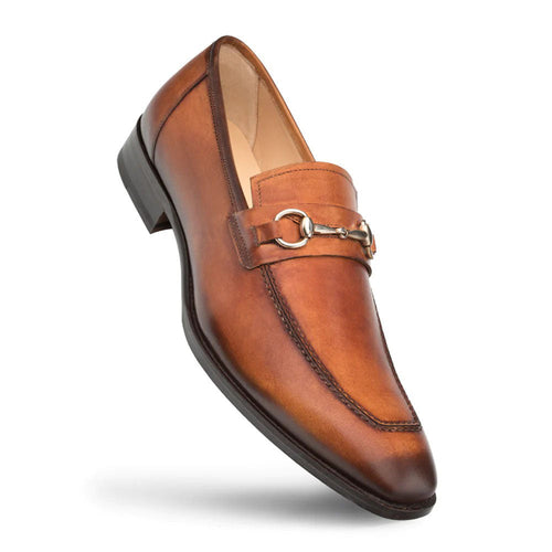 Cognac Mezlan loafers with elongated shape, slightly pointed toe, and smooth leather. Feature metallic ornament and contrast stitching. Flat, durable sole.
