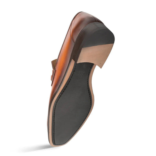 Cognac Mezlan loafers with rounded toe and low heel. Smooth, warm leather upper with decorative ornament. Textured black rubber sole with light edge.
